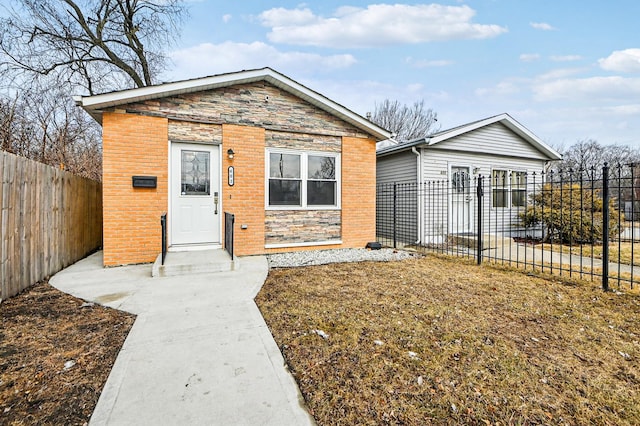 view of front of property featuring stone siding, a fenced backyard, and brick siding