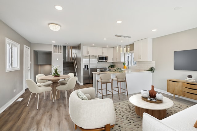 living area featuring recessed lighting, visible vents, light wood-style floors, baseboards, and stairs