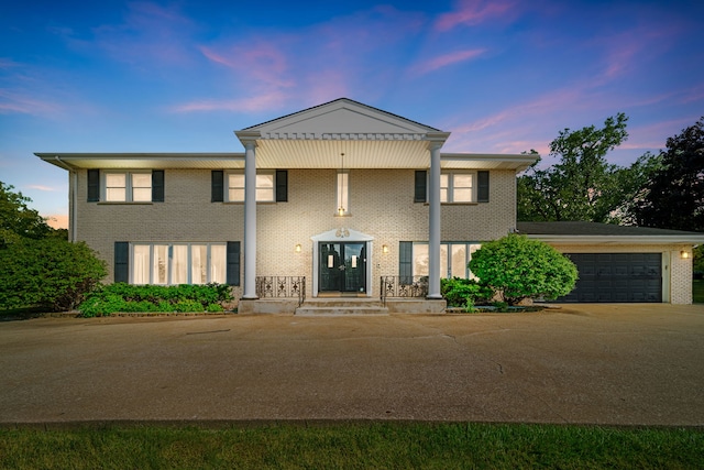 neoclassical / greek revival house with brick siding, an attached garage, and driveway