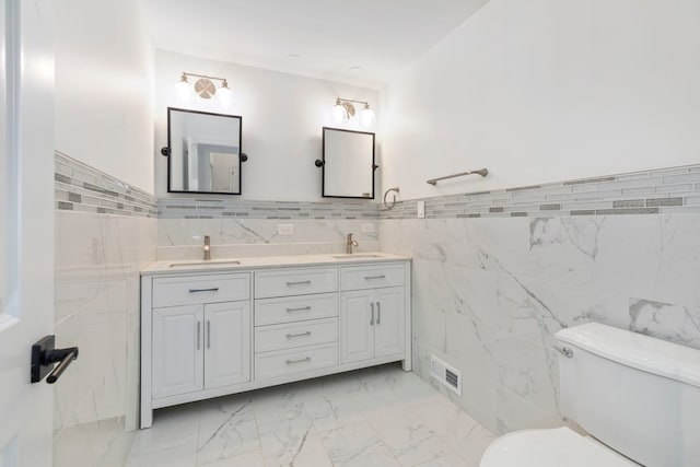 bathroom featuring toilet, marble finish floor, a sink, and visible vents