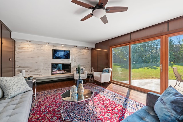 living room featuring a fireplace, ceiling fan, and wood finished floors