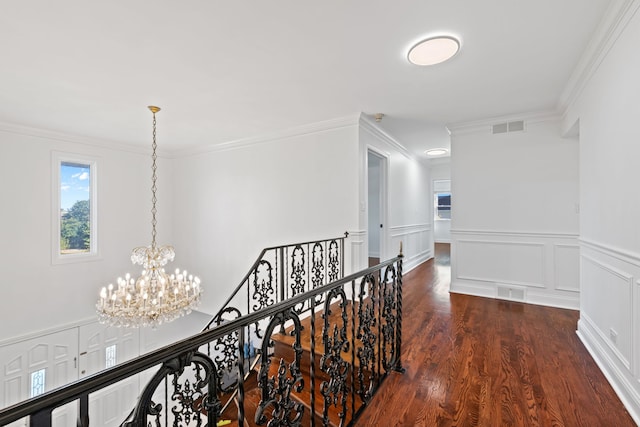 corridor with ornamental molding, dark wood-style flooring, visible vents, and an upstairs landing