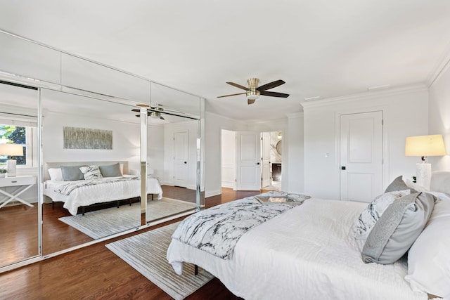 bedroom featuring a closet, dark wood-type flooring, ornamental molding, and a ceiling fan