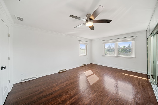 unfurnished bedroom with visible vents, baseboards, dark wood-type flooring, and crown molding