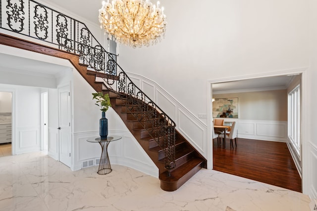 stairway featuring crown molding, a decorative wall, visible vents, and marble finish floor