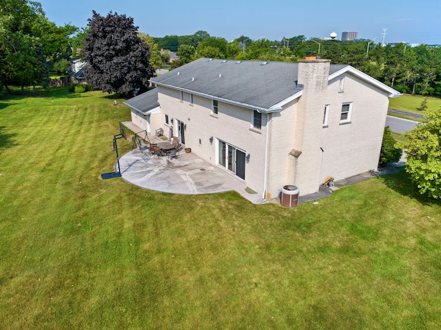 rear view of house with a patio area, a chimney, central AC unit, and a yard