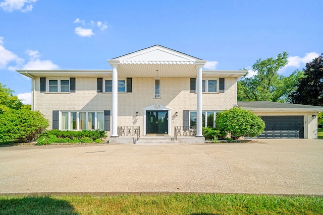 greek revival inspired property featuring brick siding and an attached garage