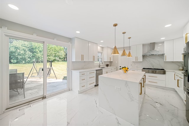 kitchen featuring a kitchen island, white cabinets, stainless steel appliances, wall chimney exhaust hood, and a sink