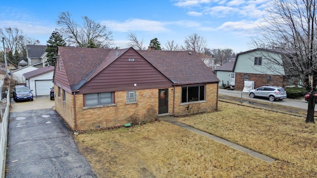 view of front facade featuring brick siding, roof with shingles, a front yard, crawl space, and an outdoor structure