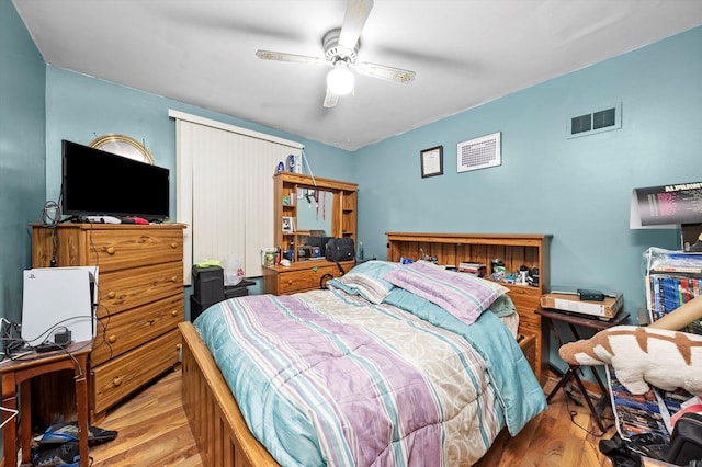 bedroom with a ceiling fan, visible vents, and wood finished floors