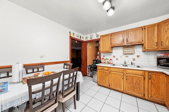 kitchen featuring light countertops, stainless steel microwave, a sink, and brown cabinetry