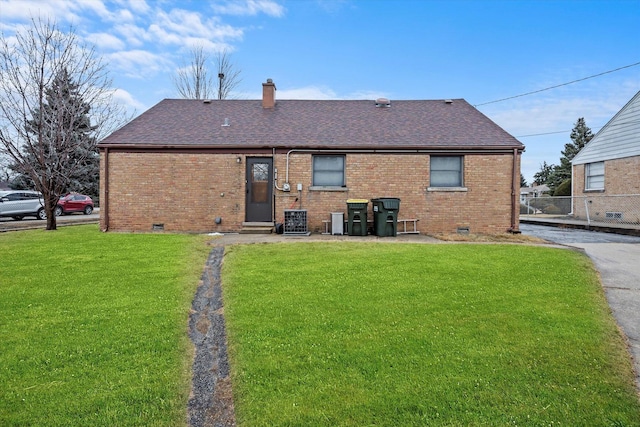 back of property featuring brick siding, crawl space, and a lawn