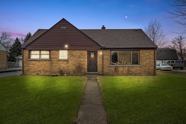 view of front facade featuring crawl space, roof with shingles, a front lawn, and brick siding