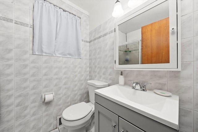 full bathroom featuring a shower with door, tile walls, visible vents, toilet, and vanity