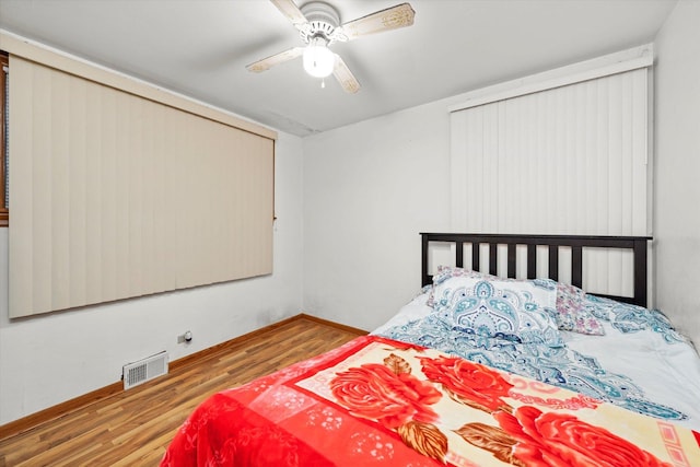 bedroom featuring ceiling fan, wood finished floors, visible vents, and baseboards