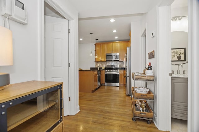 kitchen featuring hardwood / wood-style floors, sink, decorative light fixtures, stainless steel appliances, and decorative backsplash