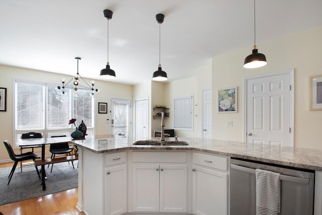 kitchen with light wood finished floors, light stone countertops, decorative light fixtures, white cabinets, and stainless steel dishwasher