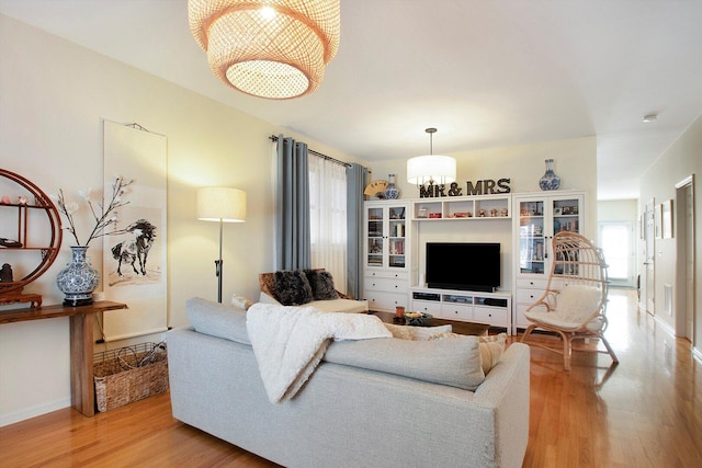 living area with light wood-style flooring, visible vents, and a chandelier