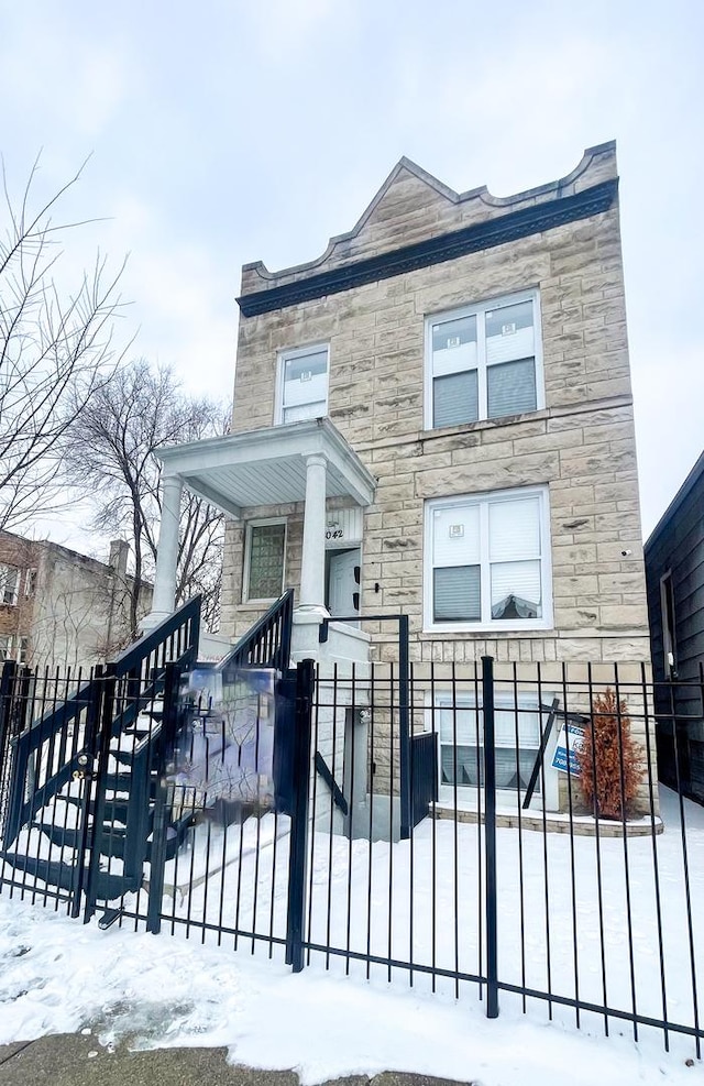 view of front facade featuring stone siding and a fenced front yard