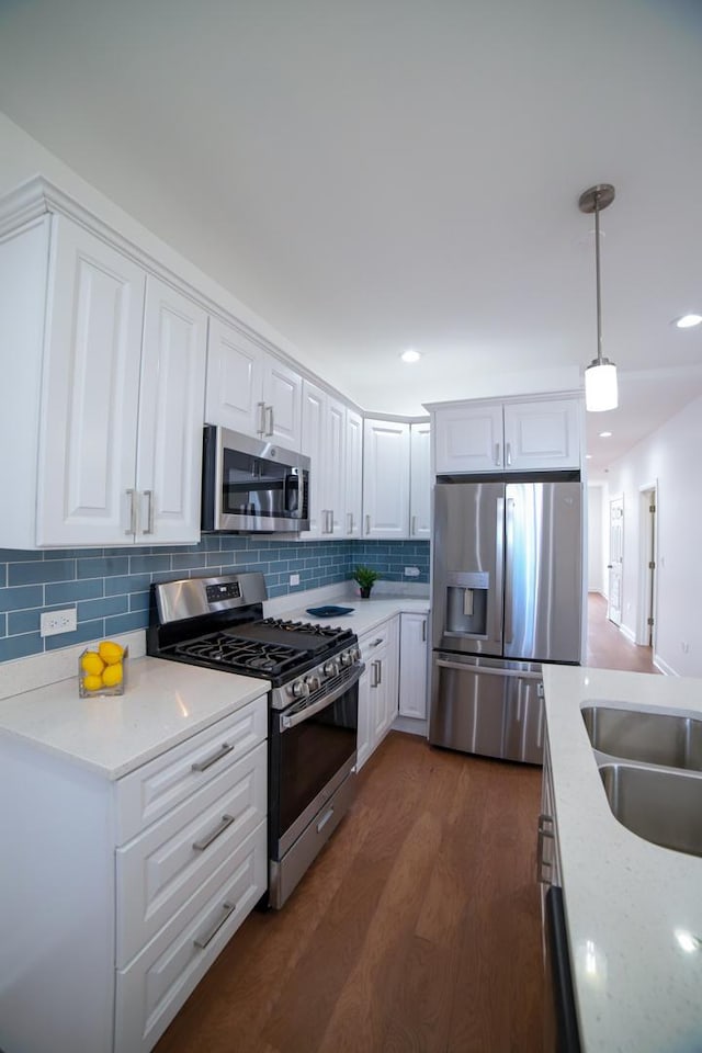 kitchen with white cabinetry, appliances with stainless steel finishes, light stone countertops, dark wood-style floors, and decorative light fixtures