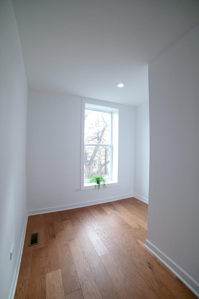 spare room with light wood finished floors, recessed lighting, visible vents, and baseboards