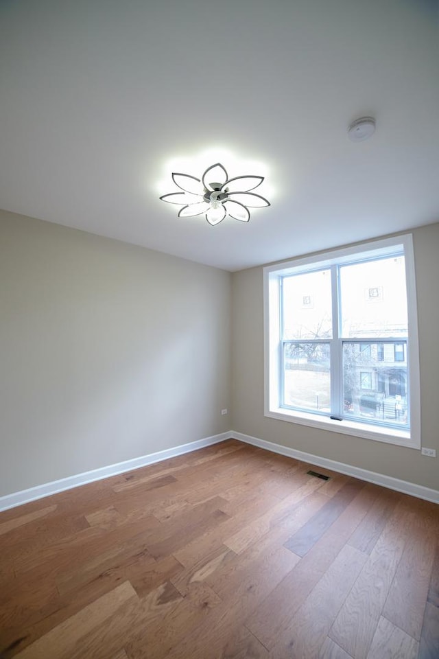 empty room with ceiling fan, light wood-style flooring, visible vents, and baseboards