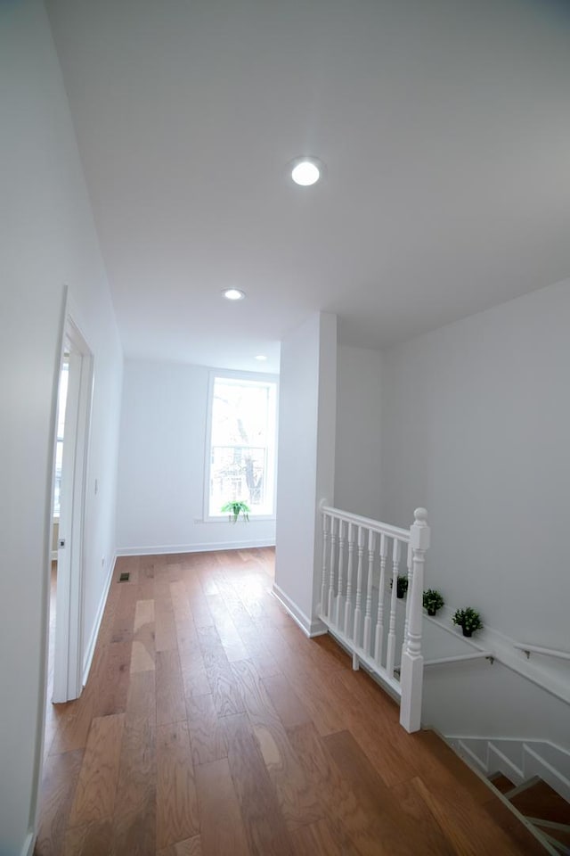 interior space with recessed lighting, wood finished floors, an upstairs landing, and baseboards