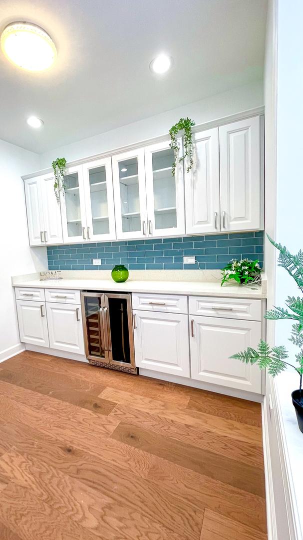 kitchen featuring light countertops, glass insert cabinets, white cabinetry, light wood-type flooring, and beverage cooler