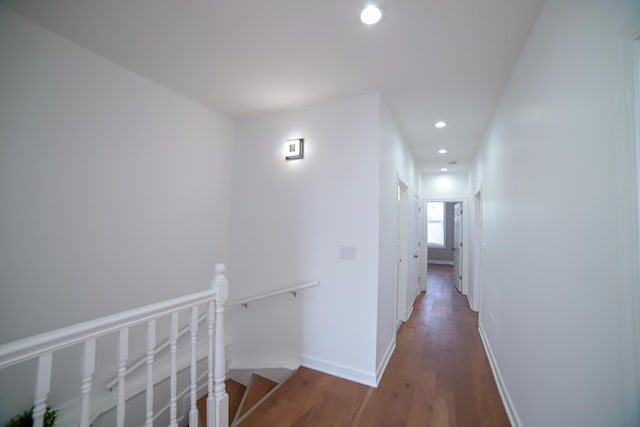 corridor with dark wood-type flooring, recessed lighting, baseboards, and an upstairs landing