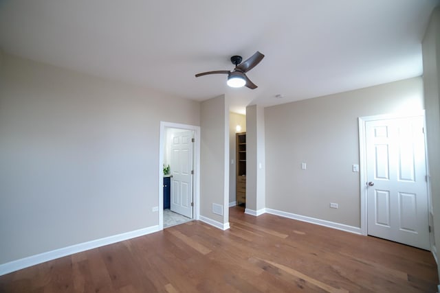 unfurnished bedroom featuring ceiling fan, wood finished floors, visible vents, and baseboards