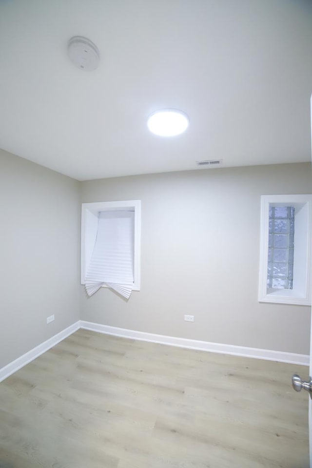 empty room featuring baseboards, visible vents, and light wood-style floors