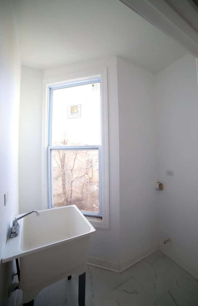 washroom with laundry area, baseboards, marble finish floor, and a sink