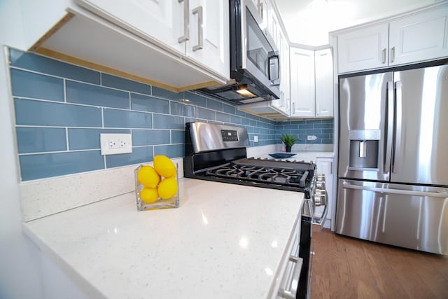 kitchen featuring tasteful backsplash, dark wood finished floors, light stone counters, stainless steel appliances, and white cabinetry