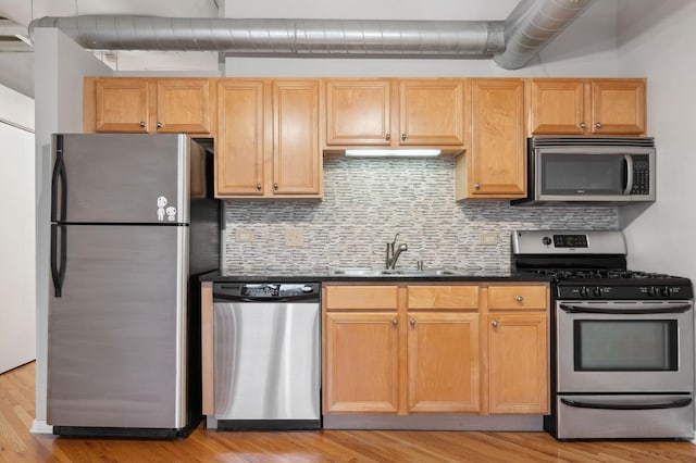 kitchen featuring appliances with stainless steel finishes, decorative backsplash, sink, and light hardwood / wood-style flooring