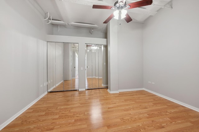 unfurnished bedroom with ceiling fan, two closets, and light hardwood / wood-style flooring