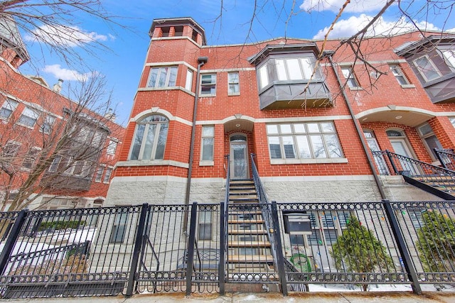 townhome / multi-family property with brick siding and a fenced front yard