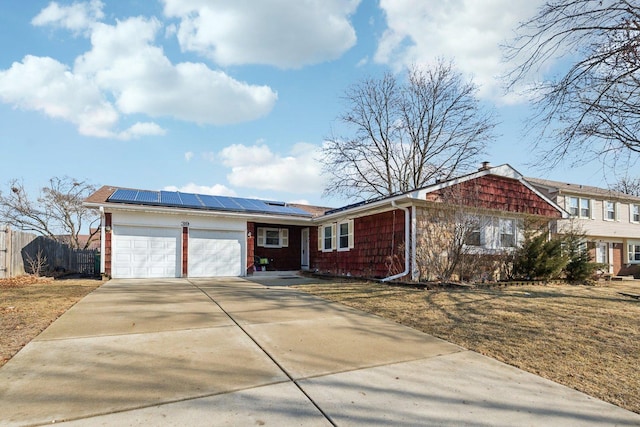 ranch-style home featuring a garage, roof mounted solar panels, fence, and concrete driveway