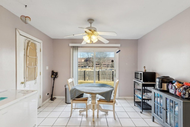 dining space featuring ceiling fan, light tile patterned flooring, and baseboards