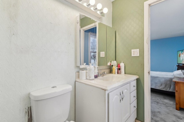 ensuite bathroom featuring toilet, vanity, ensuite bathroom, and wallpapered walls