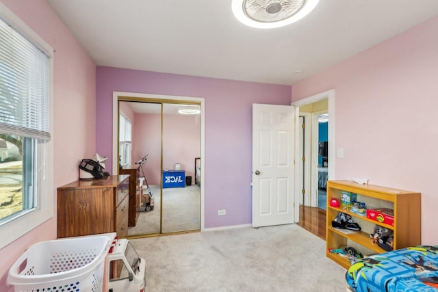 carpeted bedroom with multiple windows, baseboards, and a closet