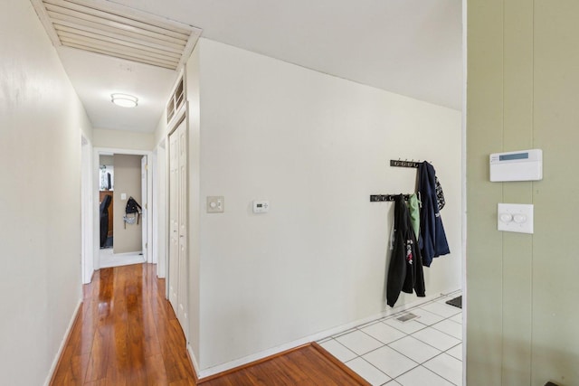 hallway featuring light wood-type flooring, baseboards, and visible vents