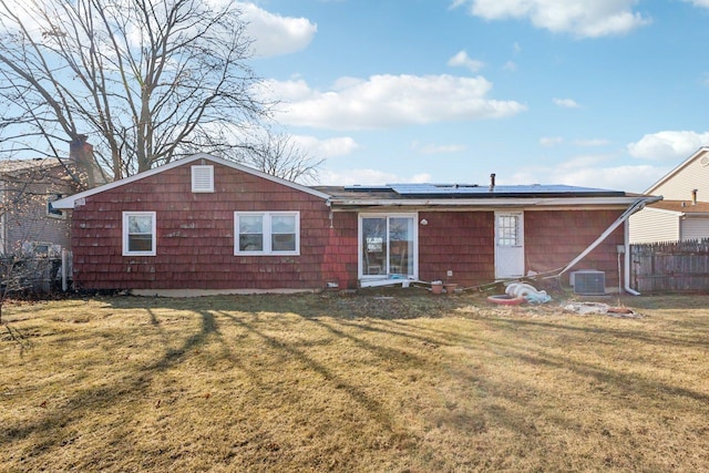 back of property featuring roof mounted solar panels, a yard, central air condition unit, and fence