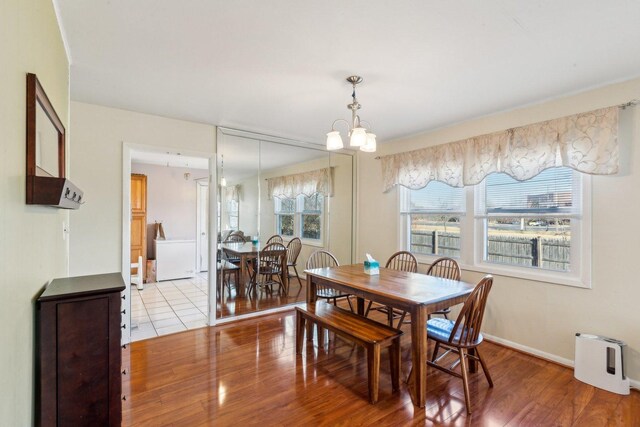 dining area featuring a chandelier, light wood-style flooring, and baseboards