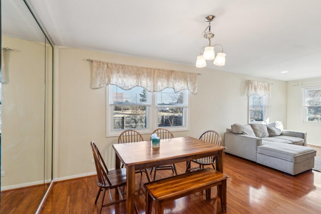 dining area featuring baseboards, hardwood / wood-style floors, and an inviting chandelier