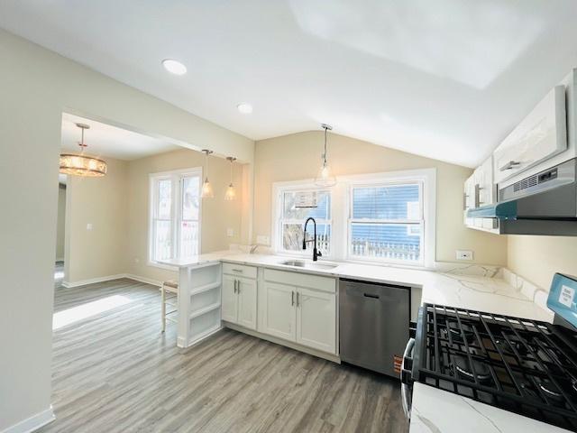 kitchen featuring stainless steel appliances, white cabinets, a sink, and decorative light fixtures