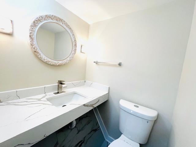 bathroom with a sink, toilet, and baseboards