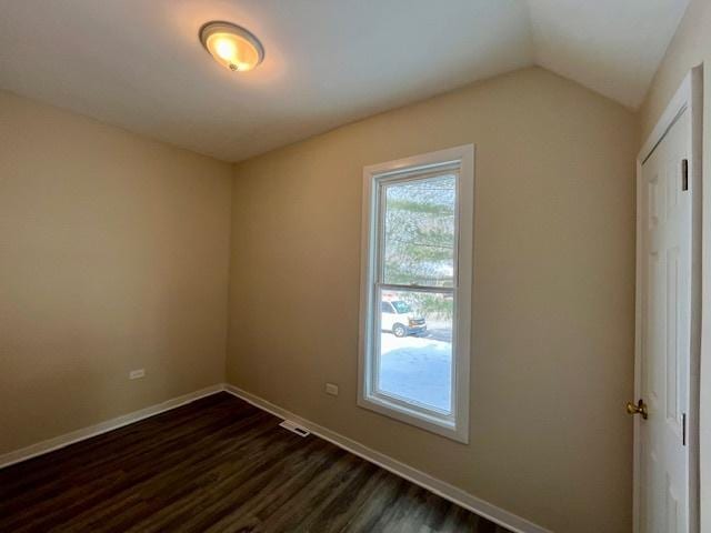 spare room featuring vaulted ceiling, baseboards, and dark wood finished floors