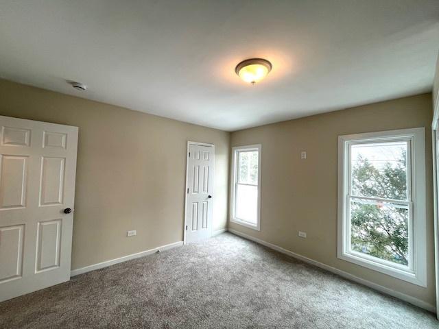 carpeted empty room featuring baseboards