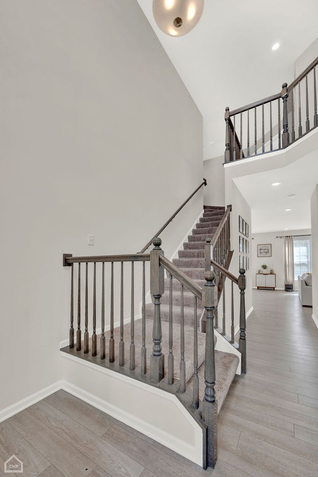 stairs with a towering ceiling and wood-type flooring