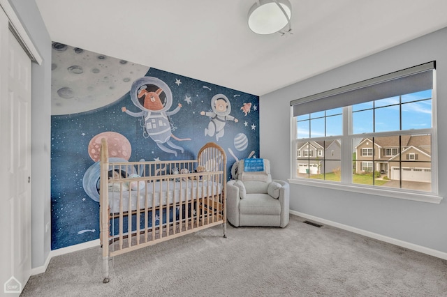 bedroom featuring a nursery area and carpet floors